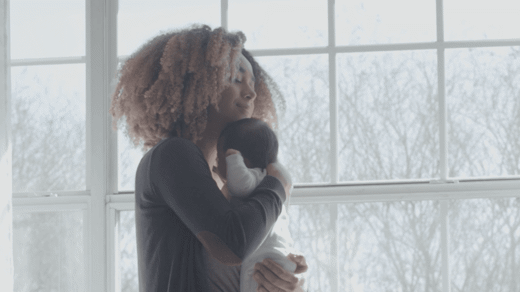 mom holding baby by window